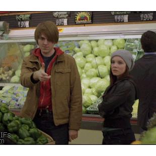 A girl at a store puts a watermelon under her shirt to look pregnant.