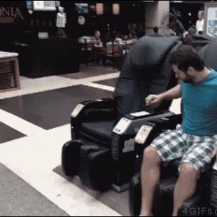 A troll pretends to get shocked by a massage chair to scare a girl.